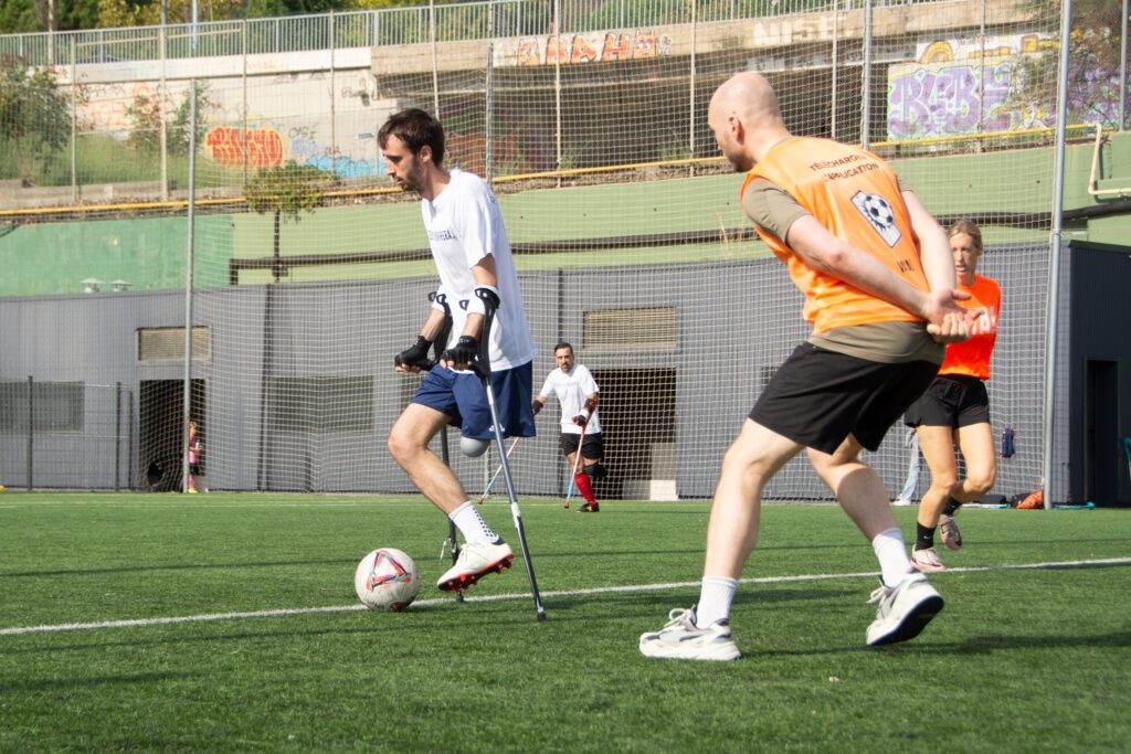 Jugador amputado con muletas en acción junto a un jugador sin discapacidad.