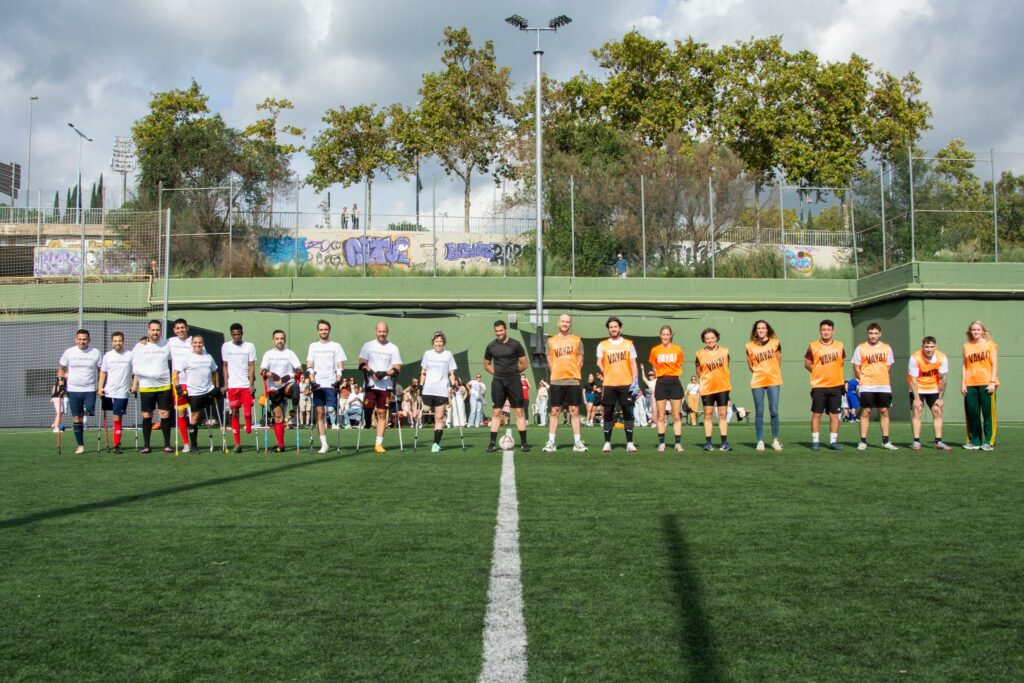 Jugadores con y sin muletas entrando al campo de fútbol en Barcelona con árbitro