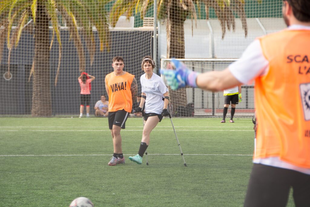 Jugadora de fútbol amputada con muletas juega con un jugador sin discapacidad con sus manos en su espalda