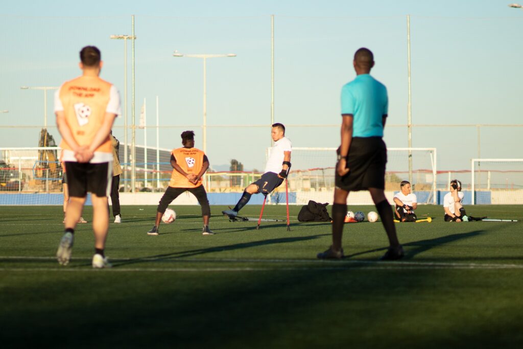 Jugadores con y sin muletas entrando al campo de fútbol en Barcelona con árbitro