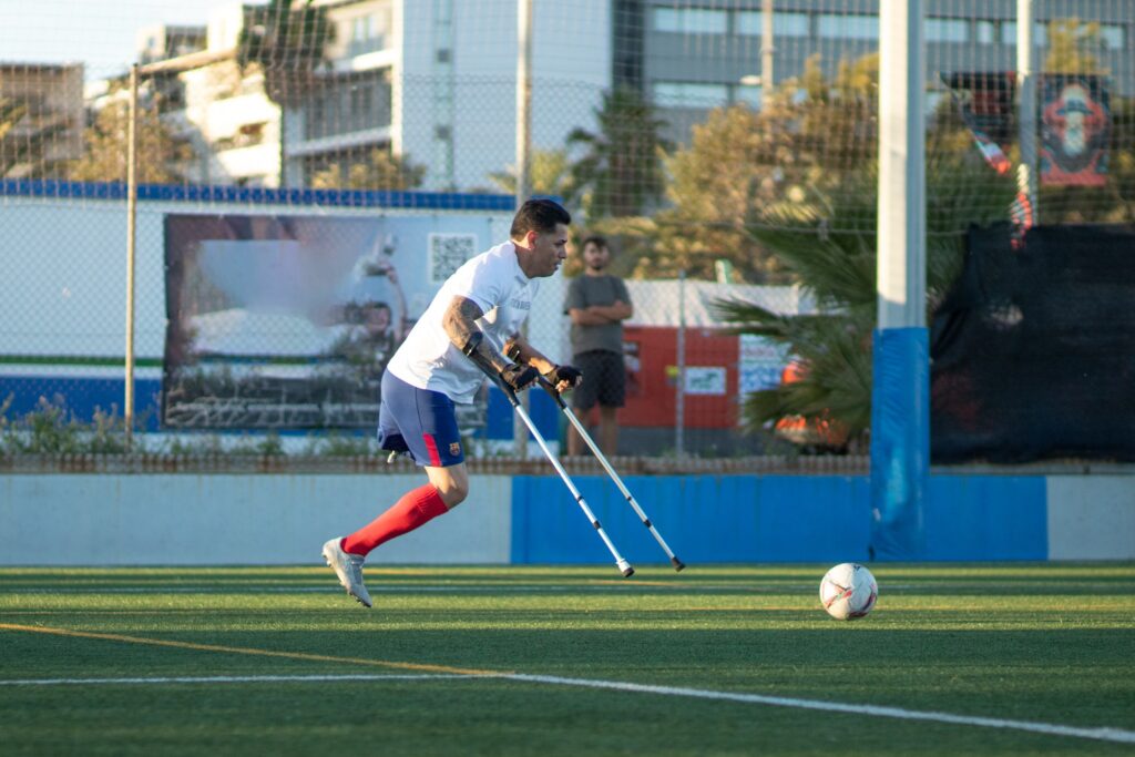 Jugador de fútbol inclusivo con muletas juega con  Equipo Sin Barreras en Barcelona.