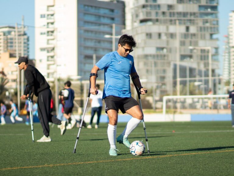 Jugador sin discapacidad con muletas en un campo en Barcelona. Equipo Sin Barreras: fútbol inclusivo.