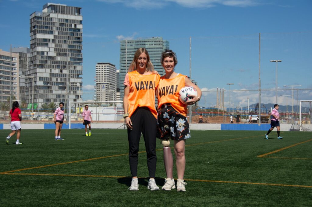 Brit y Suzan de Equipo Sin Barreras en un campo de fútbol soleado en Barcelona, con balón.