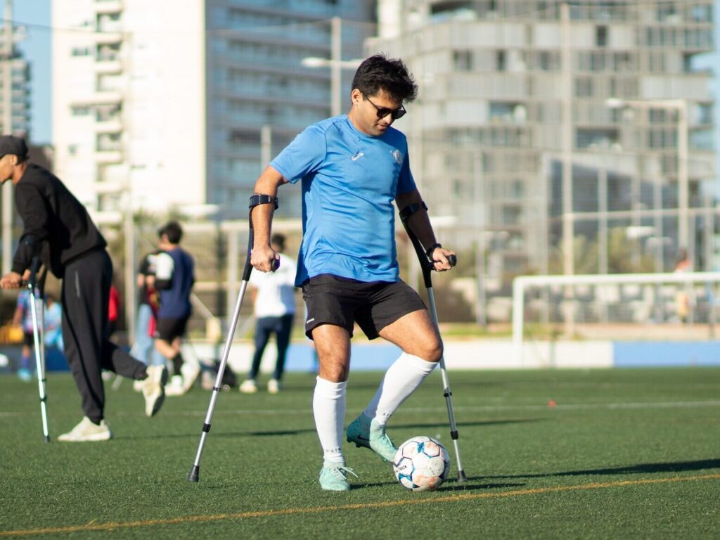 Jugador sin discapacidad con muletas en un campo en Barcelona. Equipo Sin Barreras: fútbol inclusivo.